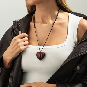 Close-up of a vintage heart-shaped wooden pendant on an adjustable black cord necklace