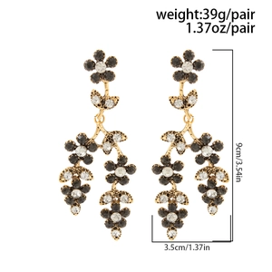 Vue détaillée de grandes boucles d'oreilles fleurs 3D en métal doré et cristaux bicolores