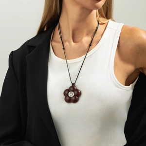 Detailed view of brown floral pendant with a sparkling crystal on a black cord necklace