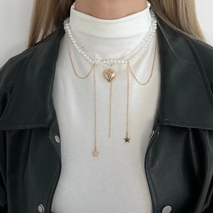 Detail view of multilayer pearl necklace with gold heart pendant and star charms on model
