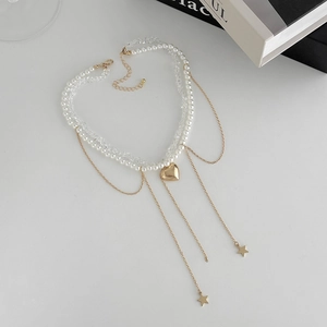 Layered pearl and crystal necklace featuring a gold heart pendant and star tassel charms