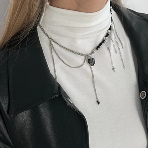 Detail of layered tassel necklace featuring a black heart pendant and silver chains