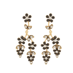 Détail de boucles d'oreilles fleurs dorées avec pétales noirs et blancs et style vintage
