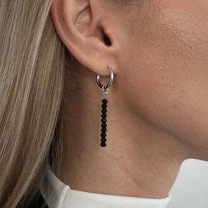 Detail of beaded drop earrings with black faceted crystals on silver metal rings