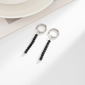 Detail of silver hoop earrings with faceted black crystal beads on a white background