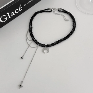 Detailed view of double-layer black beaded choker with crescent moon and star charms
