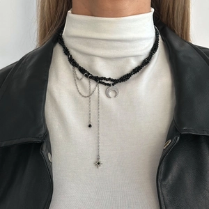 Layered black beaded choker with moon star pendants and silver tassels worn on a model