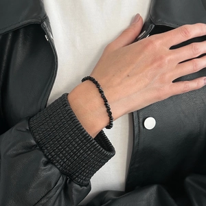 Minimalist irregular black faceted crystal bead bracelet worn with a stylish leather jacket
