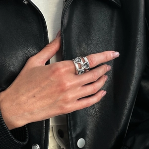 Détail d'une bague argentée avec trois pierres acryliques gris foncé sur cuir noir