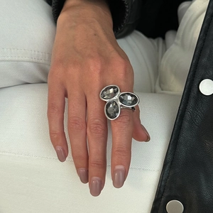 Gros plan d'une bague argentée avec trois pierres grises sur une main féminine