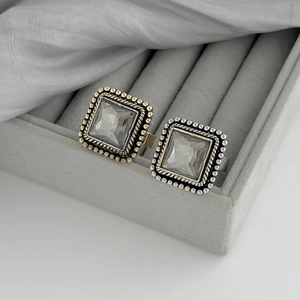 Détail de bagues cristal carré vintage avec textures métalliques et boîte à bijoux grise
