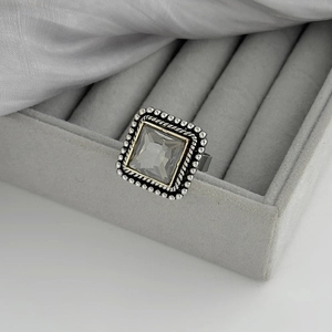 Vue macro d'une bague cocktail vintage avec pierre carrée et monture en argent vieilli