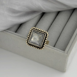 Macro d'une bague avec gemme grise carrée et métal bronze vintage dans un écrin gris