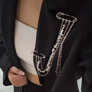Detailed view of multilayer silver tassel brooch with dual pins on a black blazer jacket