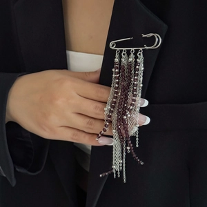 Broche épingle argentée avec perles violettes et longs glands métalliques sur un tailleur noir