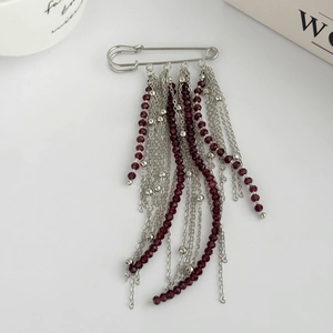Détail de la broche épingle à nourrice avec perles rouge foncé et glands de chaîne fluides