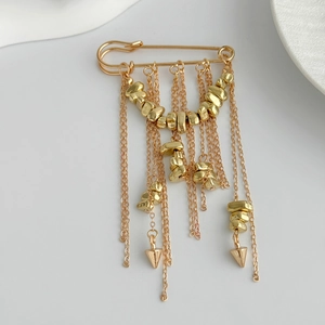 Detail of gold tassel brooch with punk fringe chains and metallic beads for women's suits