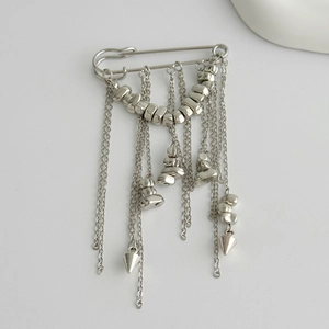 Detail of silver tassel brooch with long metal chains and beads on a minimalist background