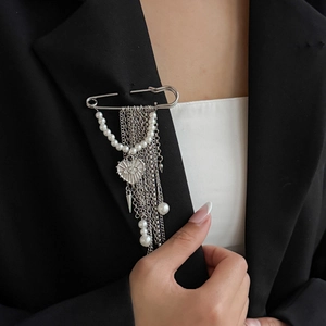 Detail of silver safety pin brooch with pearl tassels and heart charm on black suit