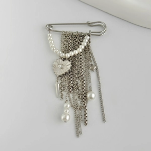 Detail of silver safety pin brooch with hanging fringe chains, pearls and heart eye pendant