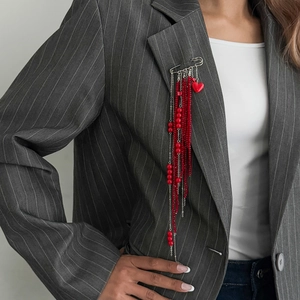 Détail de l'élégante broche à pompon en perles rouges avec pendentifs en cœur