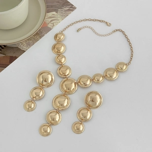 Vista dettagliata del set di collana e orecchini geometrici in oro lucido su piano