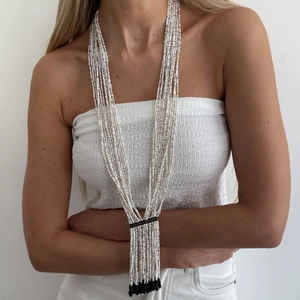 Detail view of multi-layer white seed bead necklace with black crystal tassel fringe