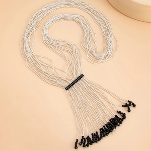 Detail of bohemian layered bead necklace featuring silver and black fringe tassels