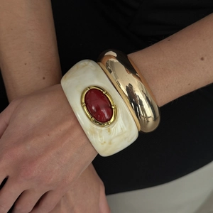 Détail du bracelet en résine marbrée crème avec pierre rouge et manchette dorée polie
