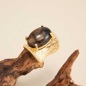 Detail of vintage gold textured wide band ring featuring a large smoky oval gemstone