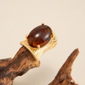 Macro detail of vintage gold wide band ring with oval brown gemstone on wood
