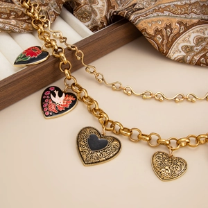 Close-up of golden chunky chain necklace featuring vintage heart-shaped enamel pendants