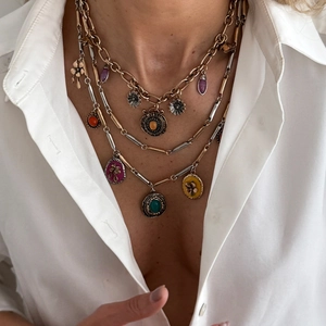 Detail view of layered bohemian necklaces with colorful charms on a white shirt