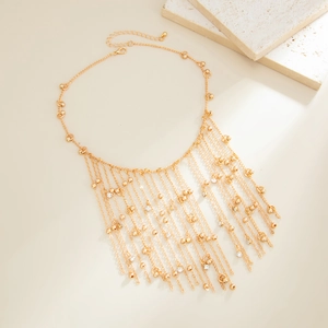 Detail view of gold fringe tassel necklace with zircon beads on a textured background