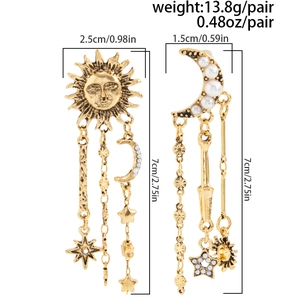 Détail de boucles d'oreilles dorées vintage avec charms soleil, lune et franges