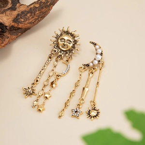 Détails macro des boucles d'oreilles célestes en or avec soleil lune et perles