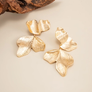 Gros plan détaillé de boucles d'oreilles feuille d'or texturées avec des nervures délicates