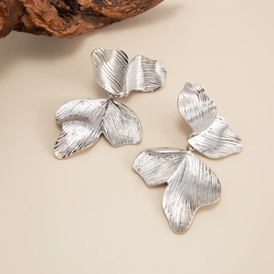Gros plan sur des boucles d'oreilles argentées avec détails métalliques radiaux gravés