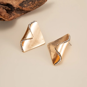 Gros plan de boucles d'oreilles dorées géométriques avec texture brossée et zircons