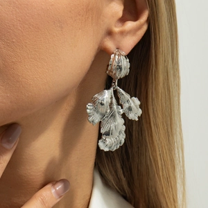Gros plan de boucles d'oreilles pétales argentés texturés portées par un mannequin