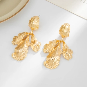 Vue détaillée de grandes boucles d'oreilles feuille dorée avec une texture martelée