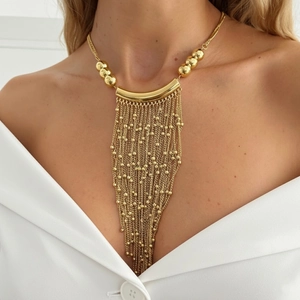 Elegant gold tassel necklace with metallic tubes and beaded chains on a model