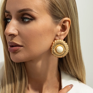 Boucles d'oreilles rondes dorées à texture spirale et résine blanche sur mannequin