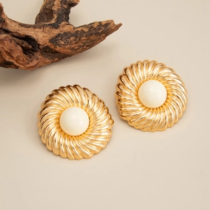Détail macro de boucles d'oreilles dorées vintage avec perles blanches sur bois