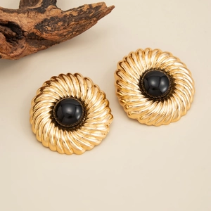 Détail des boucles d'oreilles soleil dorées en spirale avec perle noire centrale polie