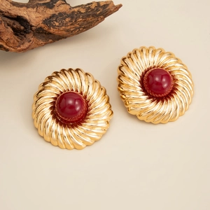 Gros plan de boucles d'oreilles dorées vintage avec perles rouges et texture en spirale