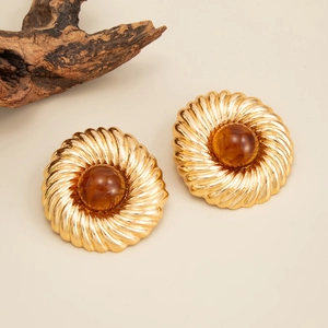 Détail de boucles d'oreilles vintage dorées avec résine ambrée et texture en spirale
