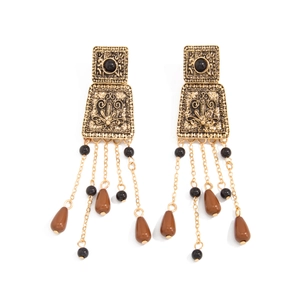 Boucles d'oreilles vintage dorées avec pampilles et pierres noires sur fond blanc