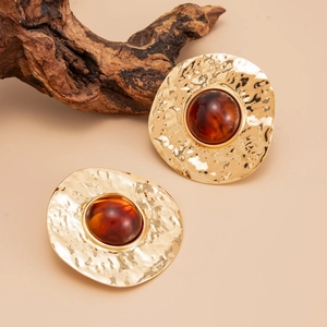 Vintage gold hammered metal earrings with amber resin inlays on a warm beige background