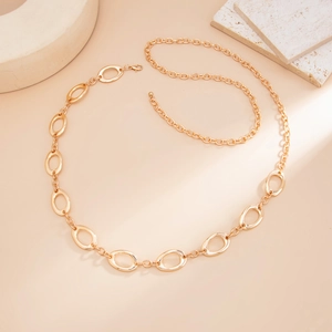 Detail of gold metal waist chain with interlocking hollow oval rings on beige background